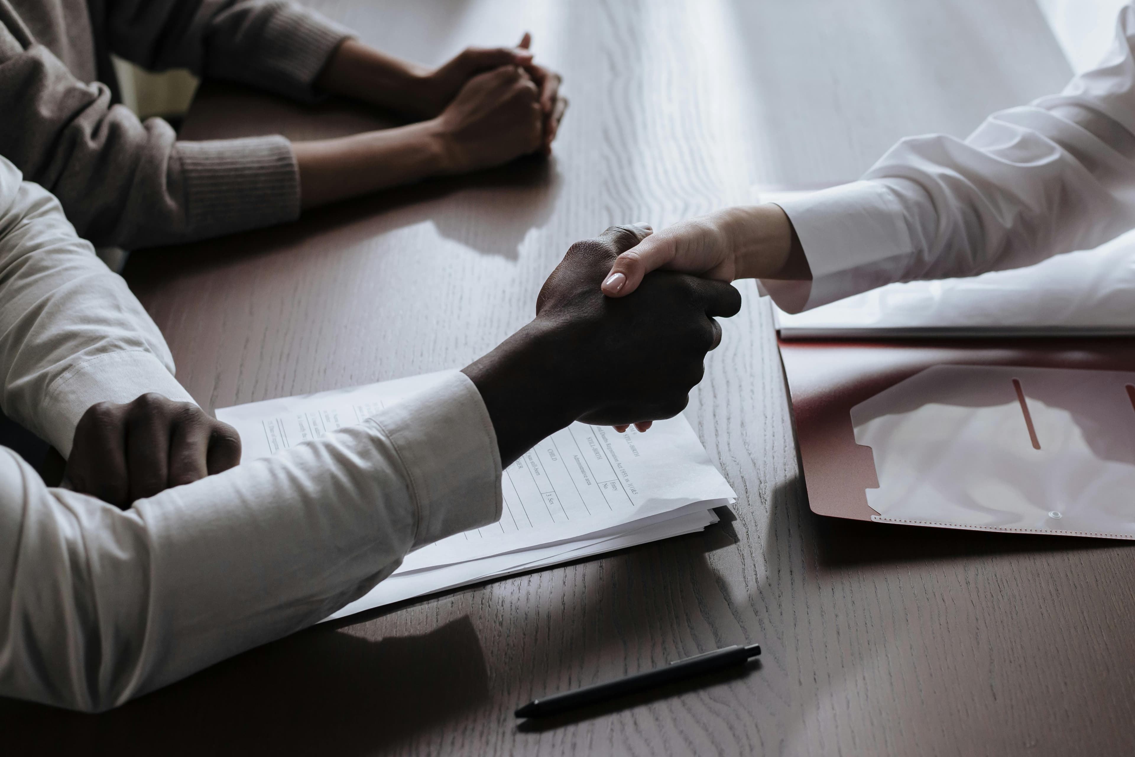 A handshake across a table of papers